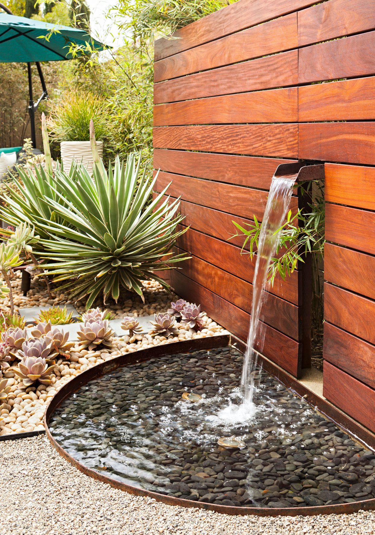 Hardscaping Services Landscaping with wooden stained wall and water feature.